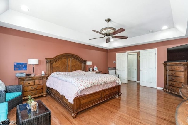 bedroom featuring a tray ceiling, recessed lighting, and light wood-type flooring