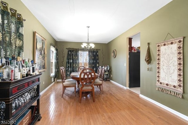 dining space with baseboards, a notable chandelier, and hardwood / wood-style floors