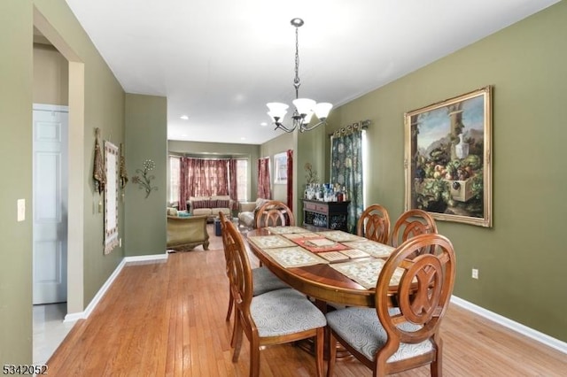 dining area with a chandelier, baseboards, and light wood-style floors