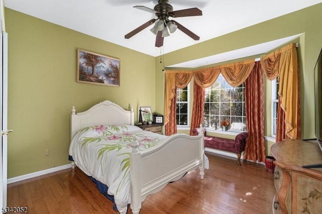 bedroom featuring baseboards, wood finished floors, and a ceiling fan