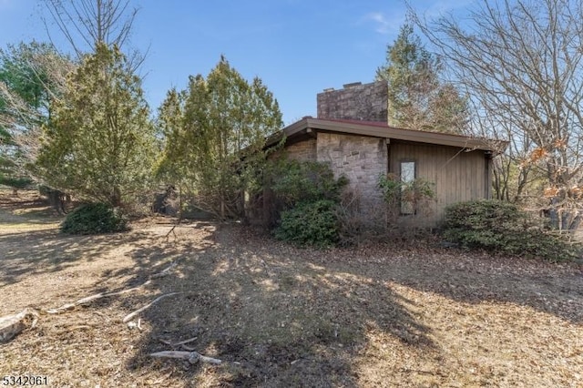 view of side of property featuring stone siding and a chimney