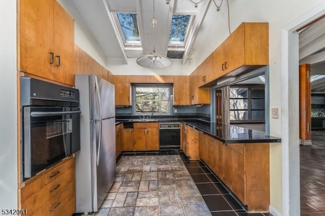 kitchen with brown cabinetry, a skylight, black appliances, and a sink