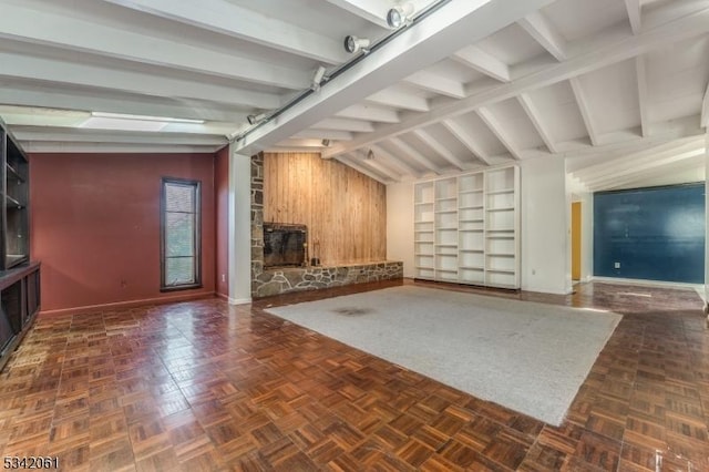 unfurnished living room with baseboards, wood walls, and vaulted ceiling with beams