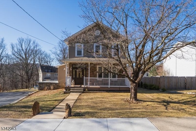 view of front facade with a porch, a front lawn, and fence