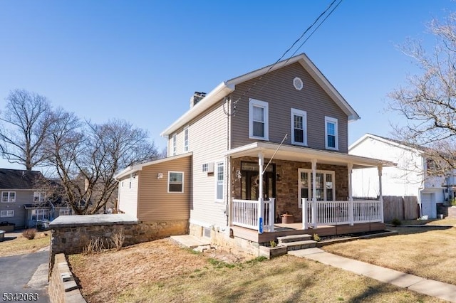 view of front of home with a porch, a front lawn, and a chimney