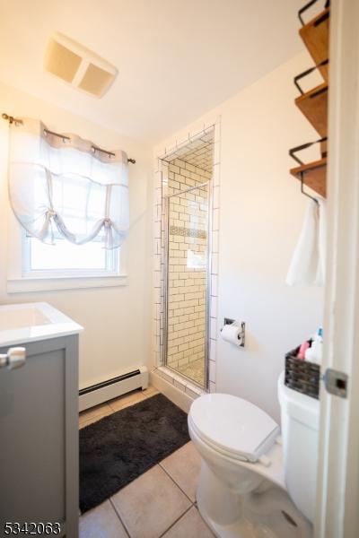 full bathroom featuring tile patterned flooring, visible vents, a baseboard heating unit, toilet, and a stall shower