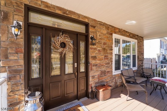 entrance to property featuring covered porch and stone siding