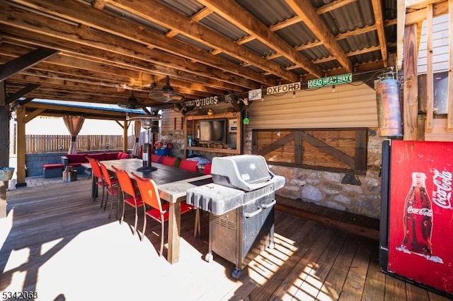 deck with outdoor dining space, fence, and a grill