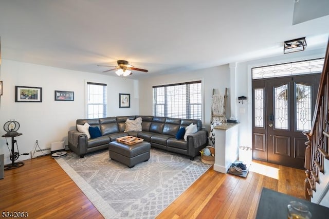 living room with baseboard heating, ceiling fan, and wood finished floors