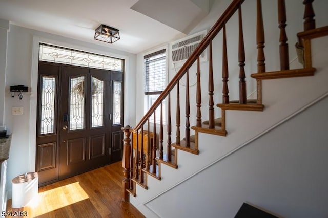 foyer featuring stairway, wood finished floors, and a wall mounted AC