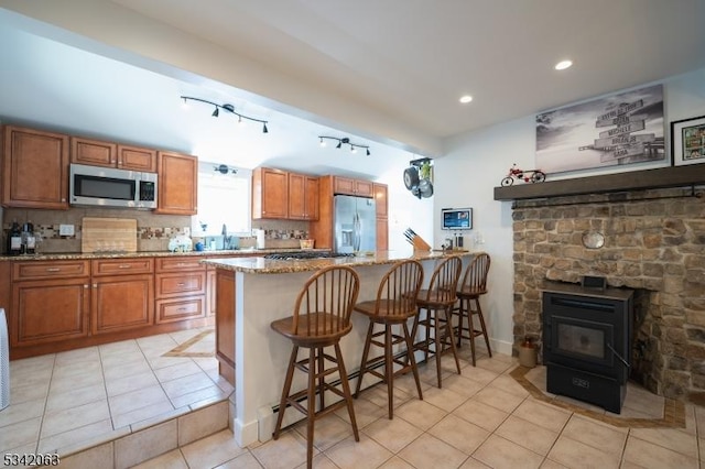 kitchen featuring stainless steel appliances, tasteful backsplash, a baseboard heating unit, and brown cabinetry