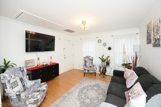 living room with visible vents, wood finished floors, and ornamental molding