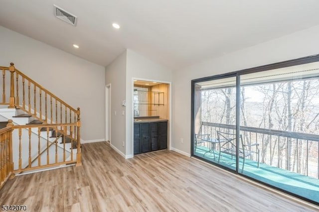 unfurnished living room featuring baseboards, visible vents, recessed lighting, vaulted ceiling, and light wood-type flooring