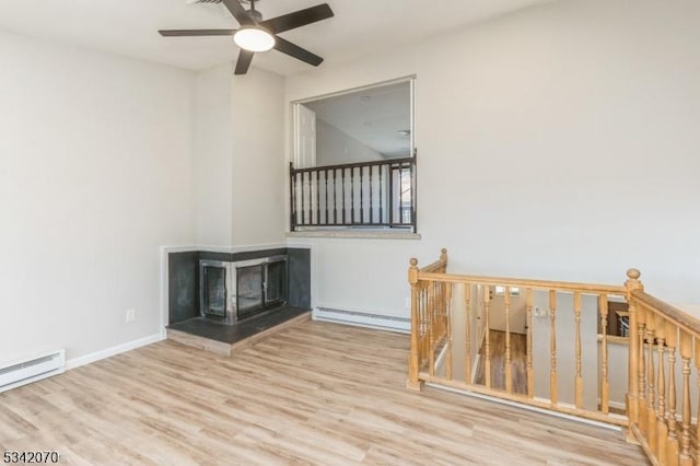 interior space featuring wood finished floors, baseboards, baseboard heating, and a multi sided fireplace