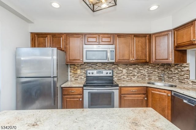 kitchen with backsplash, light stone countertops, stainless steel appliances, and a sink