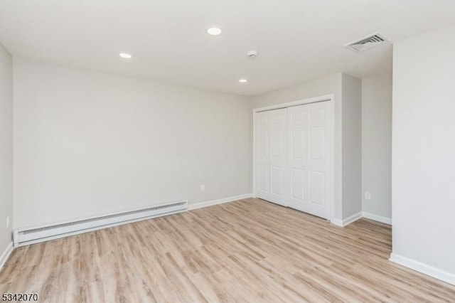 unfurnished bedroom featuring visible vents, a closet, light wood finished floors, a baseboard radiator, and baseboards