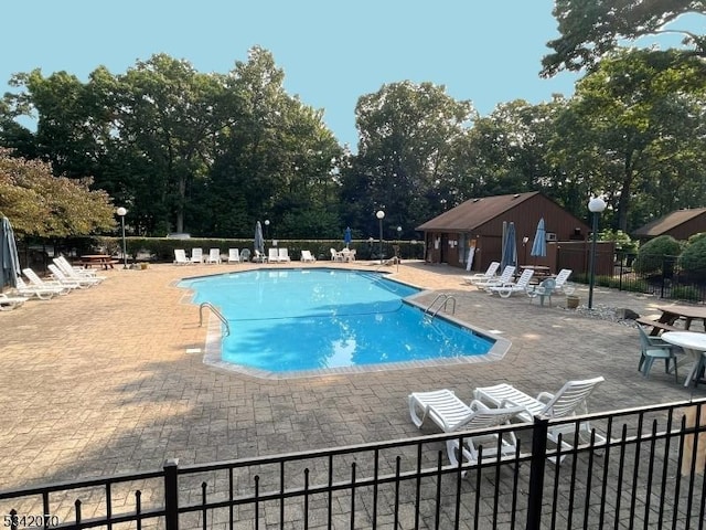 pool with a patio and fence