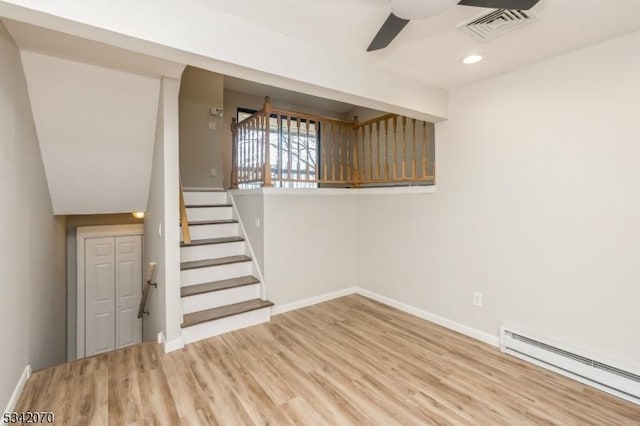 interior space with visible vents, baseboards, ceiling fan, wood finished floors, and a baseboard radiator