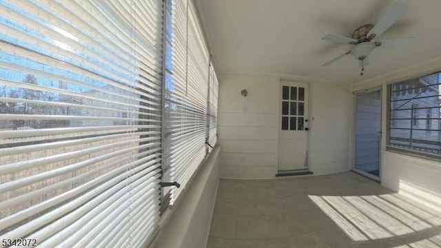 unfurnished sunroom featuring a ceiling fan