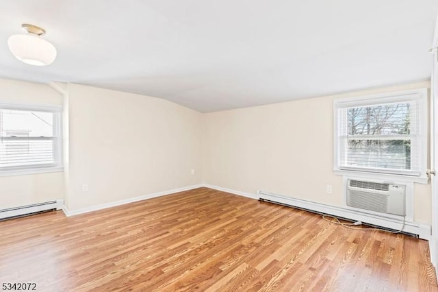 unfurnished room featuring plenty of natural light, light wood-style flooring, an AC wall unit, and baseboards