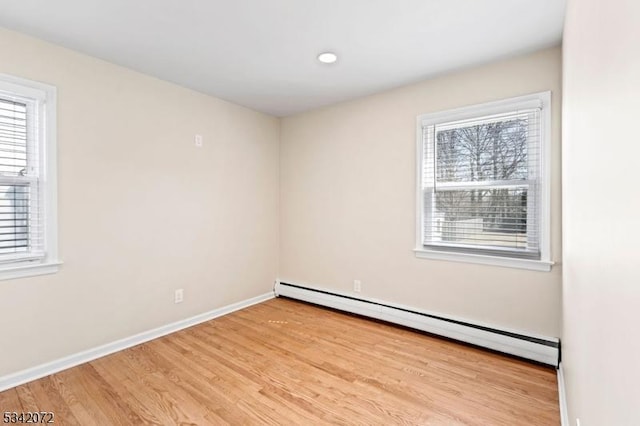 spare room with a baseboard heating unit, wood finished floors, and baseboards