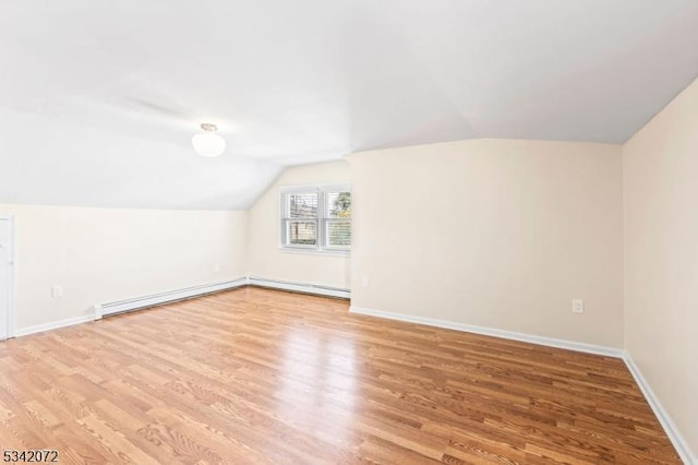 additional living space with lofted ceiling, wood finished floors, baseboards, and baseboard heating