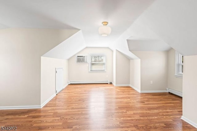 additional living space with lofted ceiling, baseboard heating, and wood finished floors