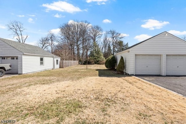 view of yard with a garage, an outbuilding, and fence