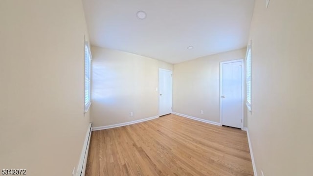 empty room with light wood-style flooring, baseboards, and a baseboard radiator