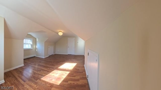 additional living space featuring baseboards, lofted ceiling, and wood finished floors