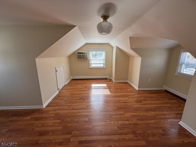 additional living space with a baseboard radiator, baseboards, wood finished floors, and vaulted ceiling