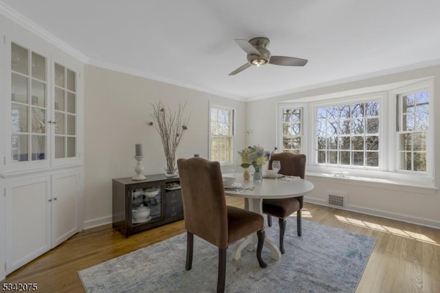 dining area with wood finished floors, visible vents, a ceiling fan, and ornamental molding