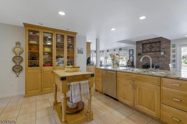 kitchen featuring a sink, glass insert cabinets, light stone countertops, dishwasher, and light tile patterned floors