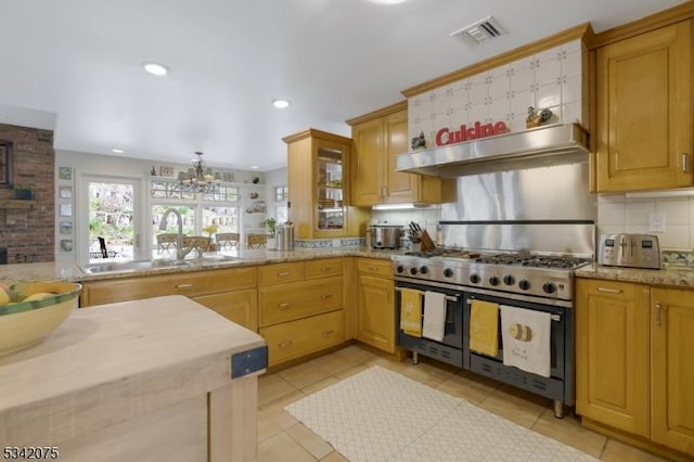 kitchen with visible vents, a sink, range with two ovens, tasteful backsplash, and a notable chandelier