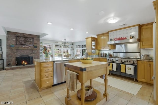 kitchen with a peninsula, under cabinet range hood, stainless steel appliances, and light tile patterned floors