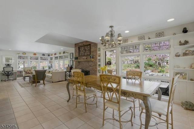 dining space featuring an inviting chandelier, a brick fireplace, plenty of natural light, and light tile patterned floors