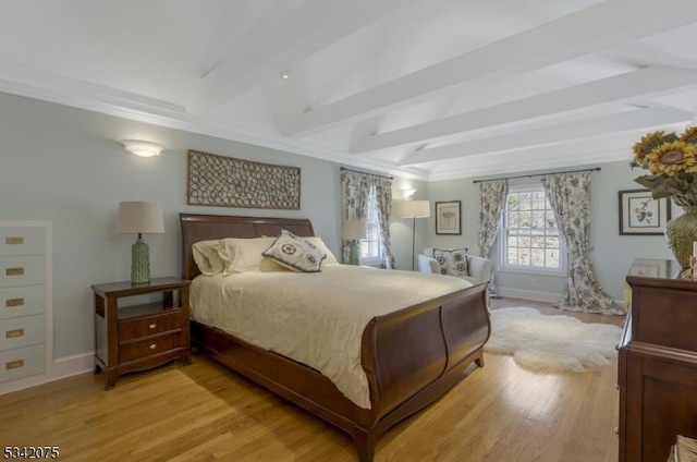 bedroom with baseboards, beam ceiling, and light wood-style floors