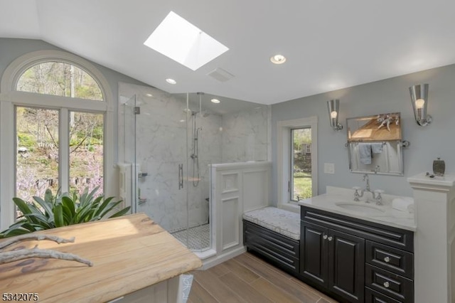 bathroom with vaulted ceiling with skylight, a marble finish shower, and plenty of natural light