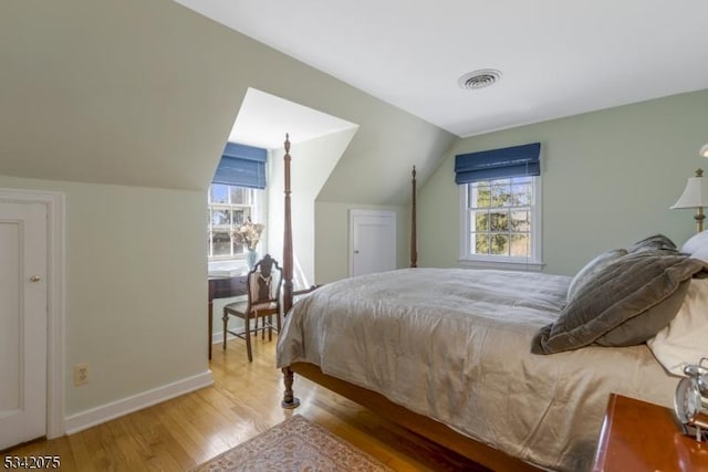 bedroom featuring wood finished floors, visible vents, lofted ceiling, and baseboards