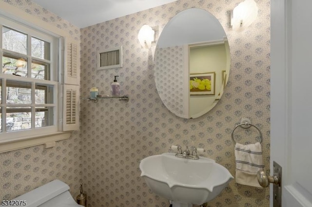 bathroom featuring toilet, a sink, and visible vents