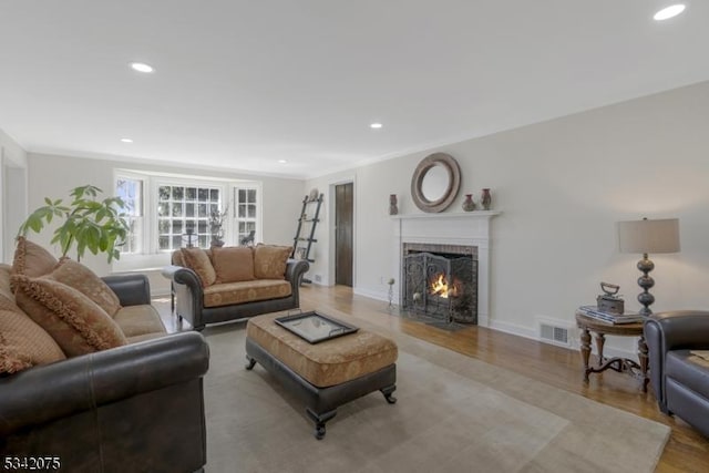 living room with a brick fireplace, light wood-style floors, visible vents, and recessed lighting