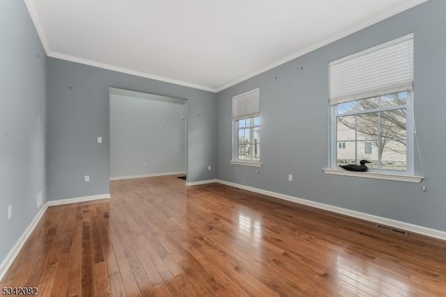 empty room with wood-type flooring, visible vents, and baseboards