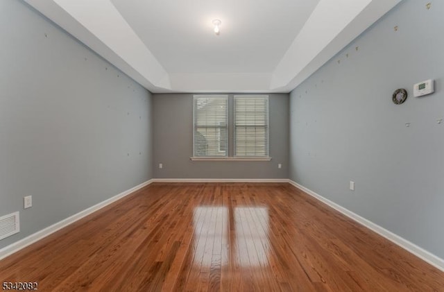 spare room with baseboards and hardwood / wood-style flooring