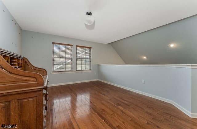 bonus room featuring lofted ceiling, dark wood-type flooring, and baseboards