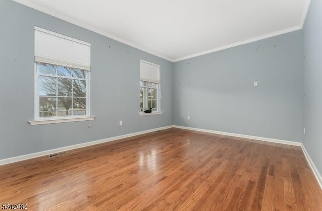 empty room featuring ornamental molding, visible vents, plenty of natural light, and baseboards