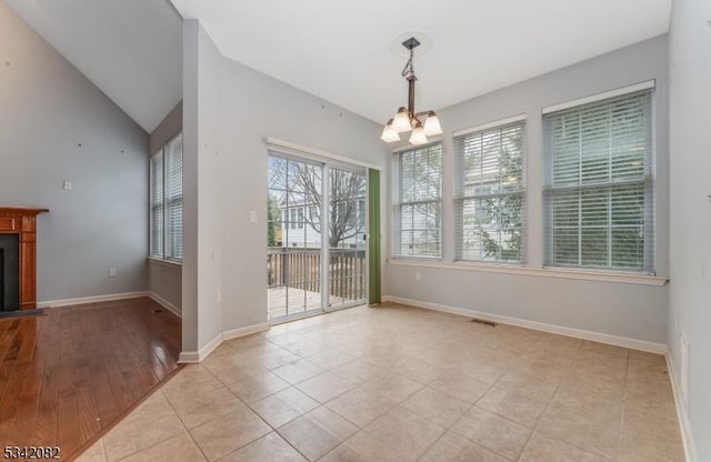 unfurnished dining area with a fireplace with flush hearth, visible vents, baseboards, vaulted ceiling, and an inviting chandelier