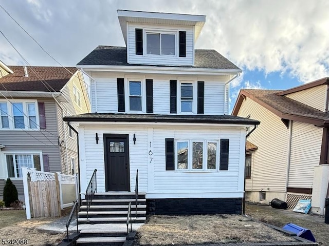 american foursquare style home with a shingled roof and fence