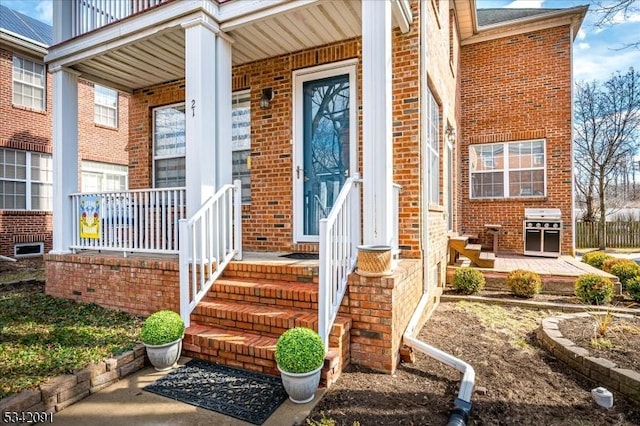 entrance to property with covered porch and brick siding