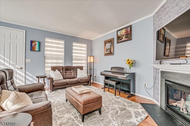 living room featuring ornamental molding, a large fireplace, baseboards, and wood finished floors