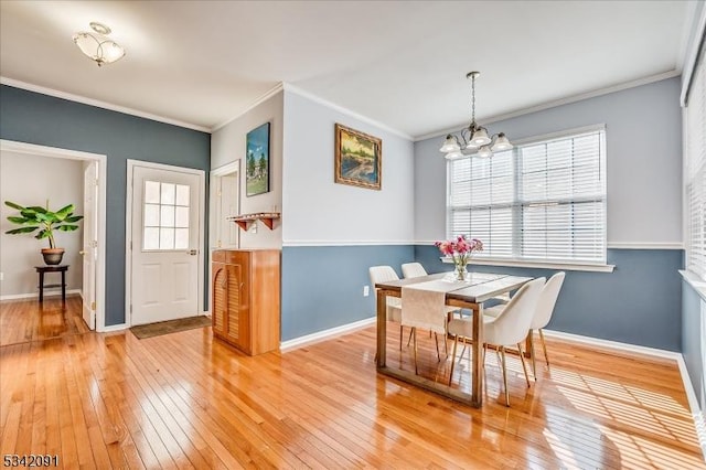 dining space with light wood-type flooring, crown molding, baseboards, and an inviting chandelier